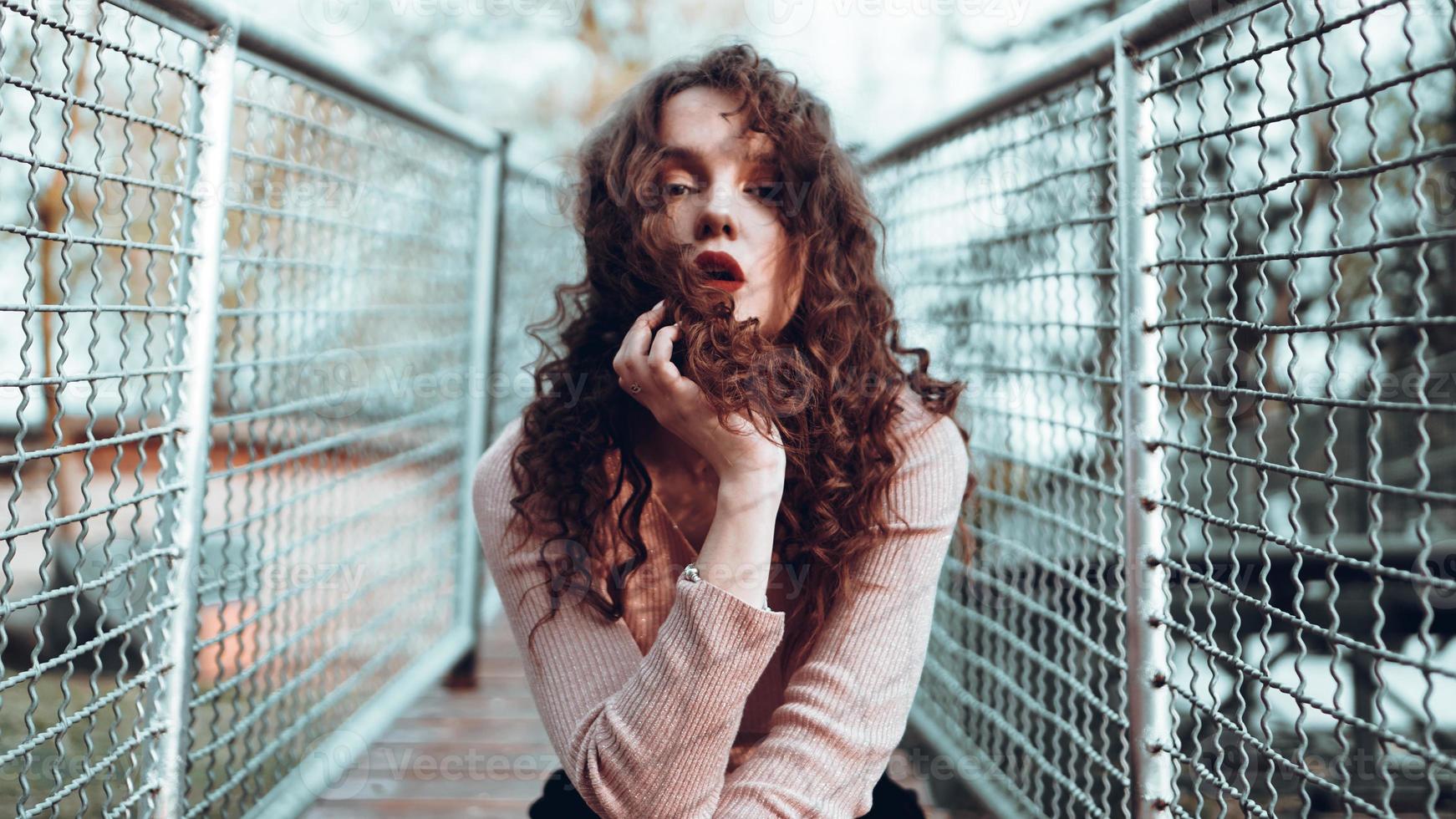 Retrato de moda de moda joven sentado cerca de la red rabitz foto