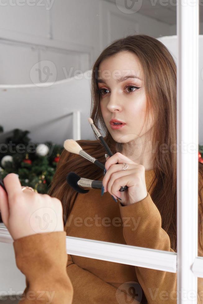 Artista de maquillaje sosteniendo una brocha para polvos, reflejo en el espejo foto