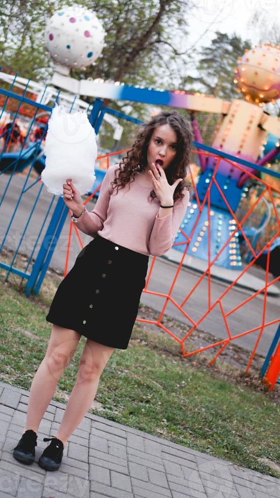 Smiling excited girl holding cotton candy at amusement park photo