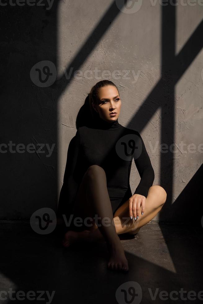 mujer sensual en el suelo junto a la ventana, una sombra sobre ella foto