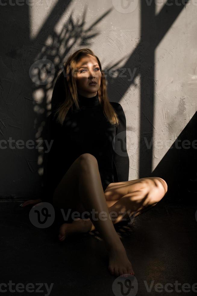Sensual woman on the floor next to the window, a shadow on her photo