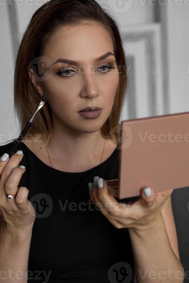 Close up portrait of a woman. She herself puts makeup on her face photo