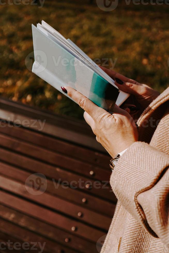 Woman in an autumn coat holds a book. Autumn park photo