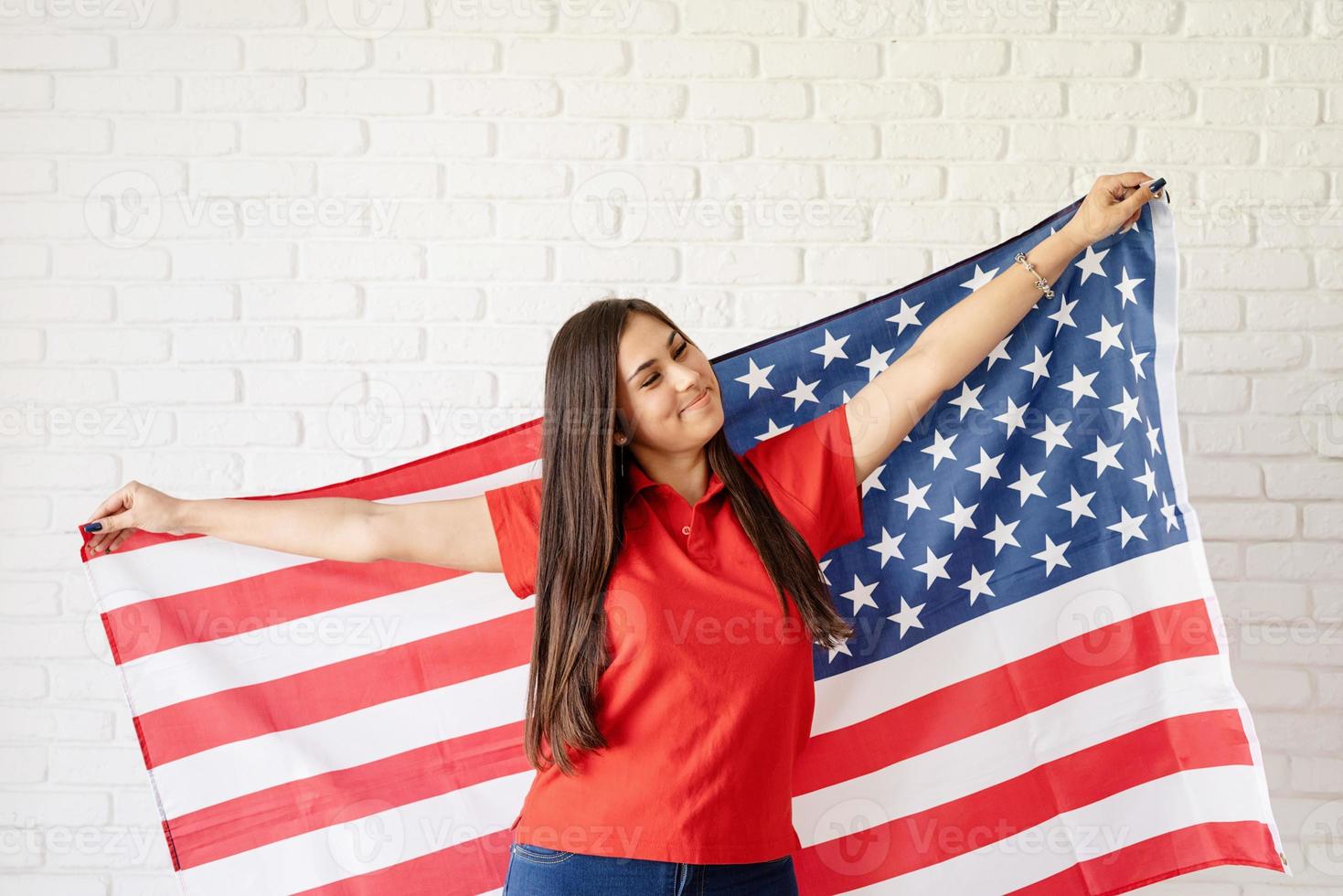 hermosa mujer joven con bandera americana, brazos extendidos foto