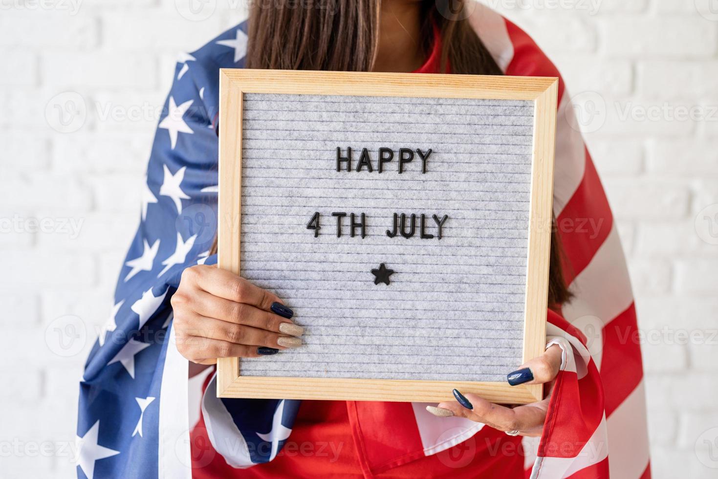 Woman with flag holding letter board with words Happy 4th July photo