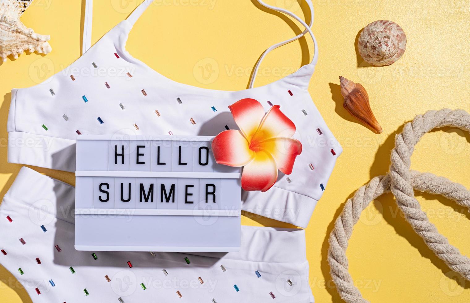 Words hello summer on the lightbox with swimming suit, tropical photo