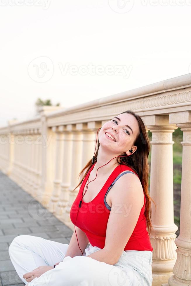 Girl sitting next to column fencing listening to the music photo