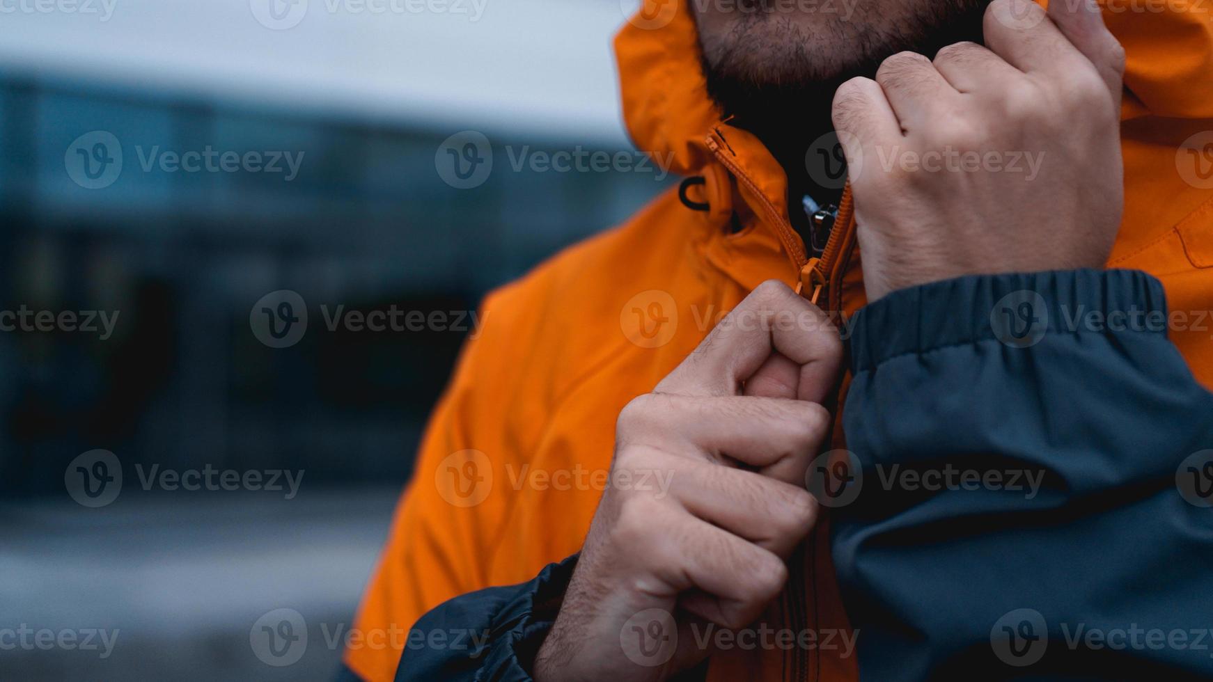 A man fastens his work uniform. Orange worker uniform - close up photo