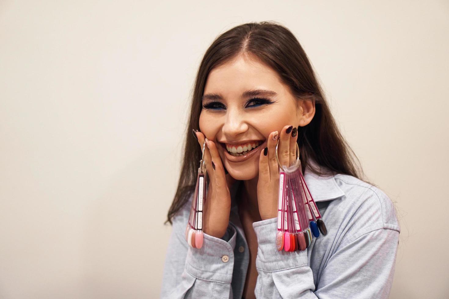 mujer sonriente, sosteniendo una paleta de esmalte de uñas de manicura y pedicura foto