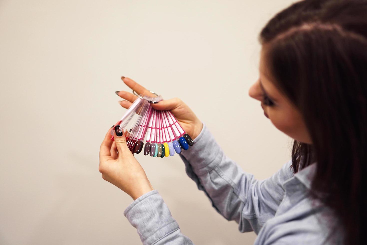 la niña elige el color del esmalte para manicura. probadores de uñas foto