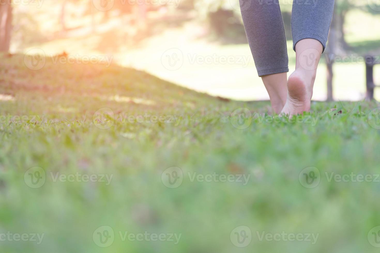 Barefoot woman walking on green grass in park photo