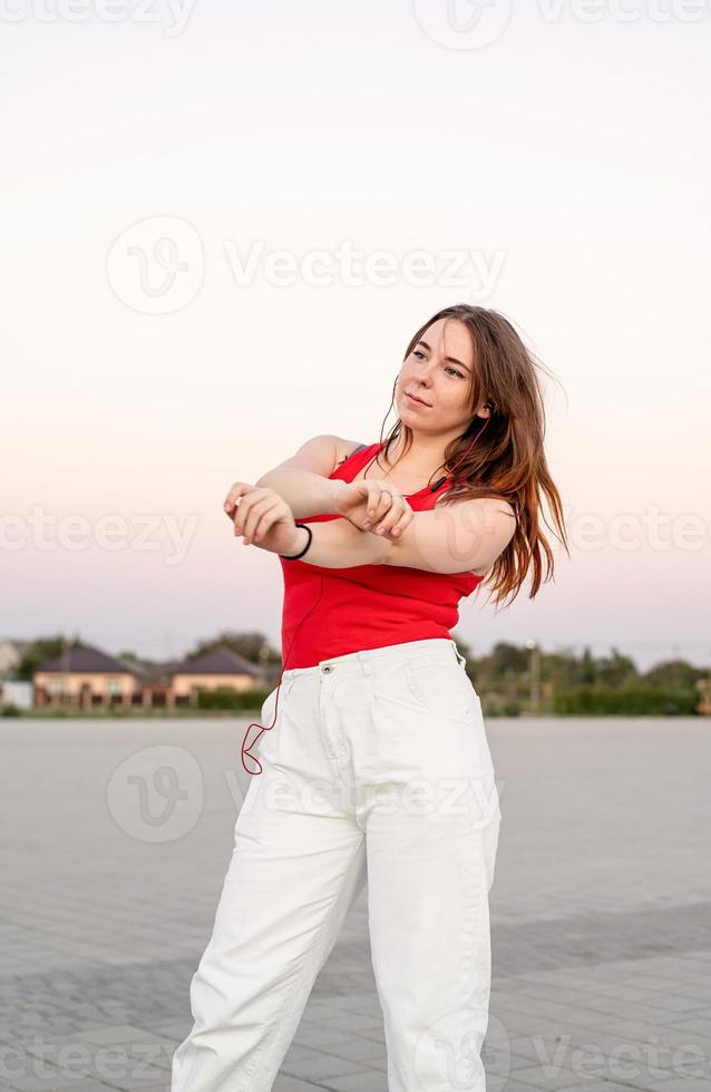 Teenage girl listening to the music dancing in the park photo