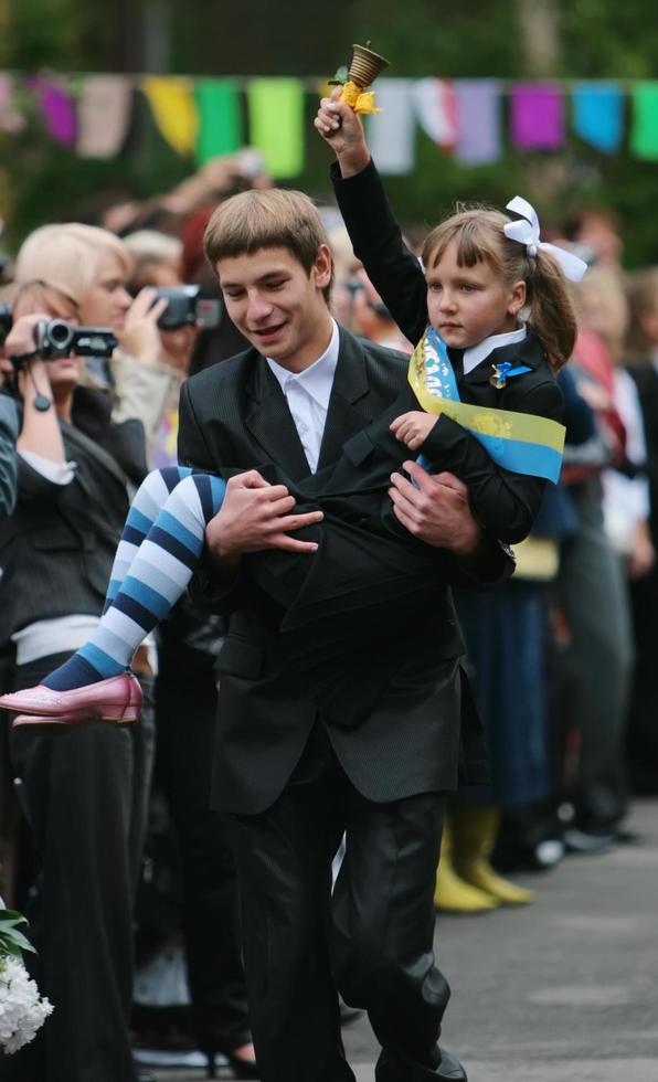 Ukraine, Kiev 2008- The senior pupil bears a first-grader who rings at the bell, informing about the beginning of the new school year photo