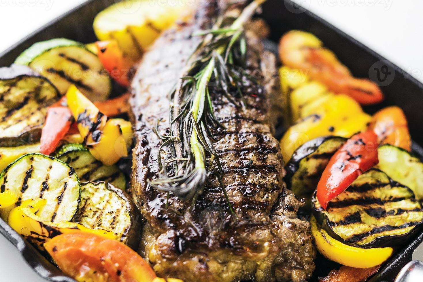 Greek organic lamb steak with grilled vegetables and herbs in sizzling skillet photo