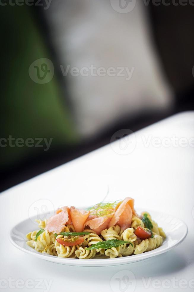 Ensalada de pasta fresca de salmón ahumado con tomate orgánico y albahaca con salsa de crema de ricotta y eneldo foto