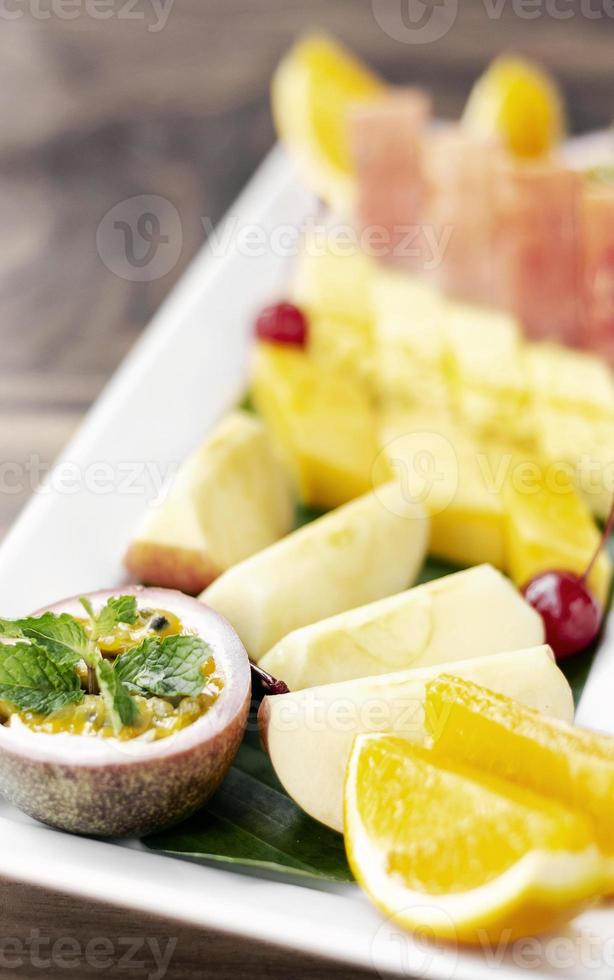 Plato de ensalada de frutas orgánicas frescas cortadas mixtas al aire libre en la mesa de madera foto