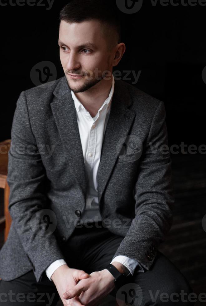 Portrait of a young handsome elegant man on dark background photo