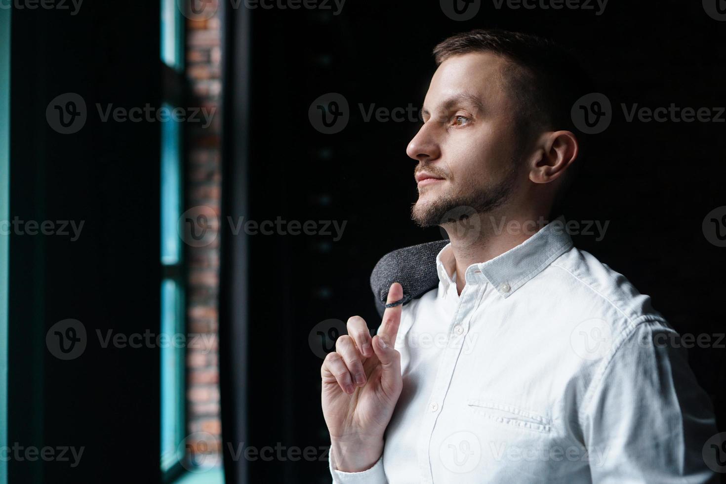 Ver en el perfil de un joven empresario de pie cerca de la ventana foto