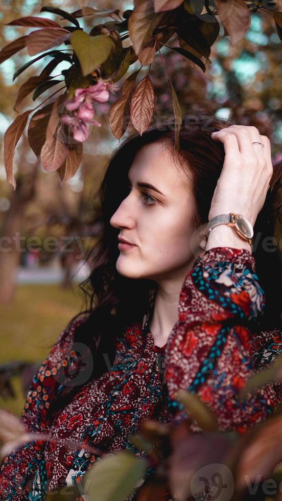 hermosa mujer joven en hojas de Borgoña foto