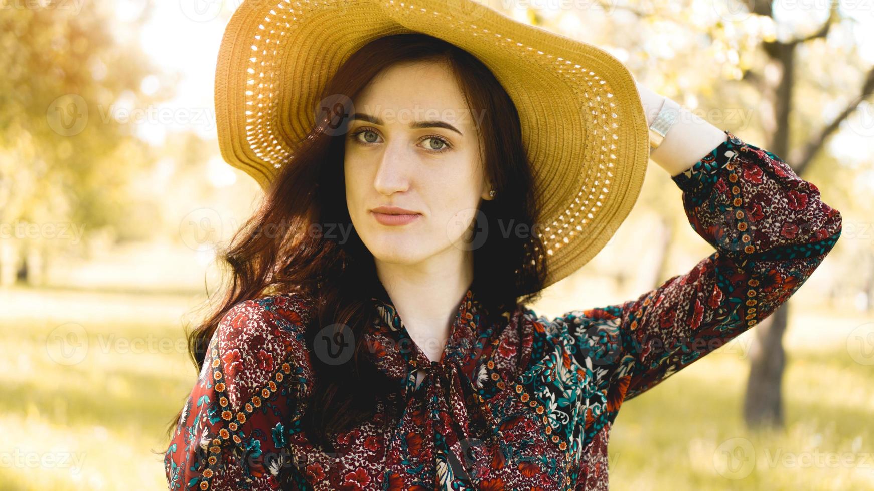 Beautiful young woman wearing straw hat at sunset time photo