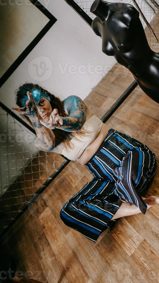 Hermosa artista de pelo largo en taller con maniquíes foto