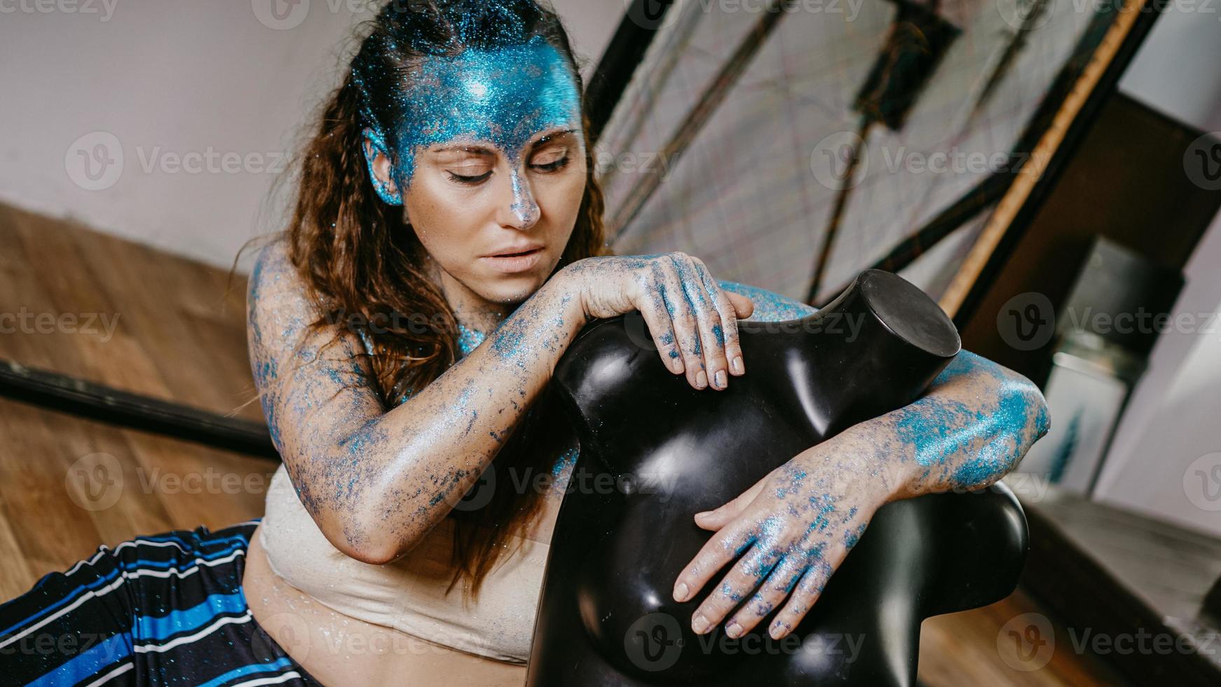 Long-haired beautiful artist in workshop with mannequins photo