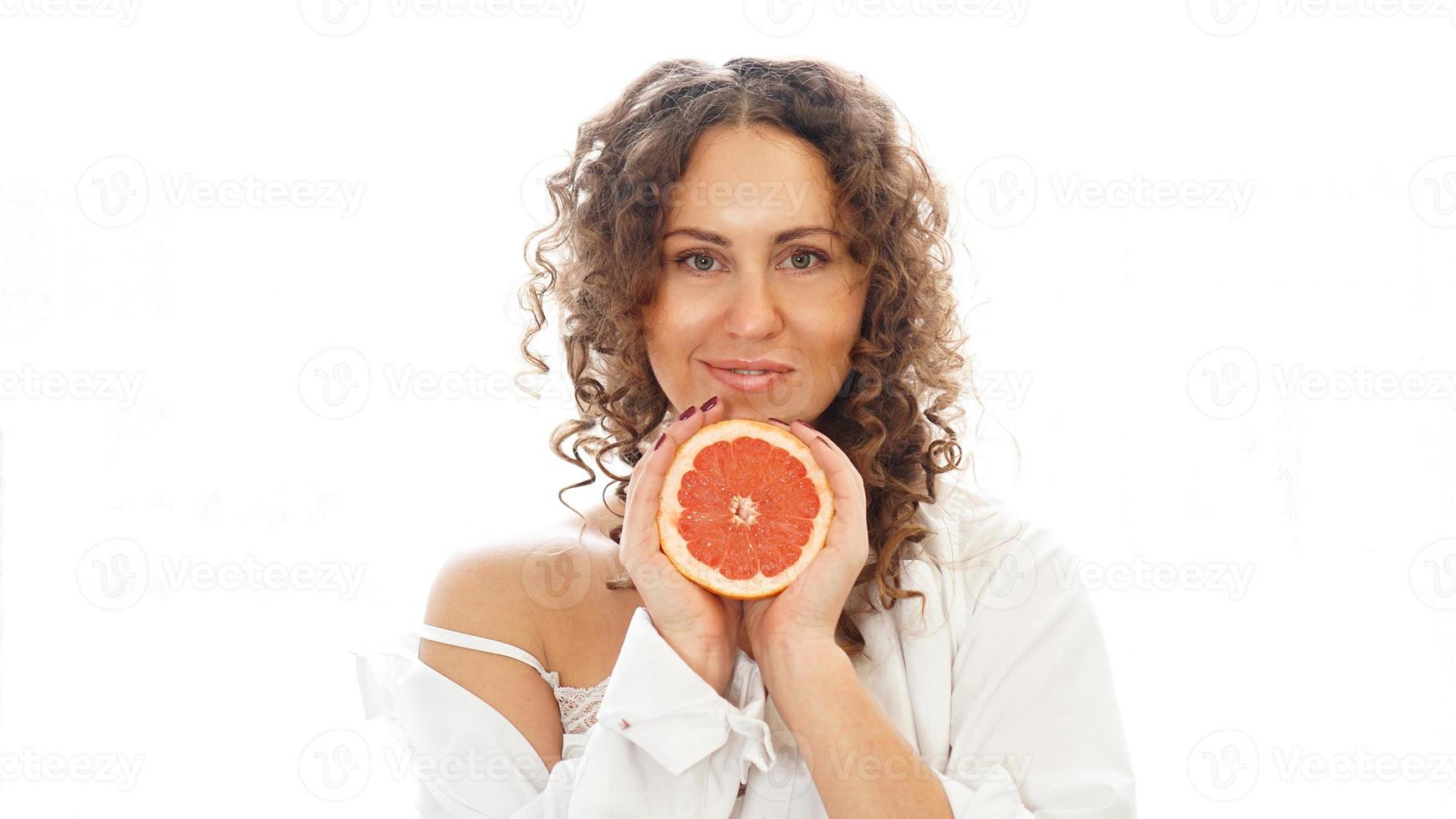 Portrait of pretty middle-aged woman with curly hair with grapefruit photo