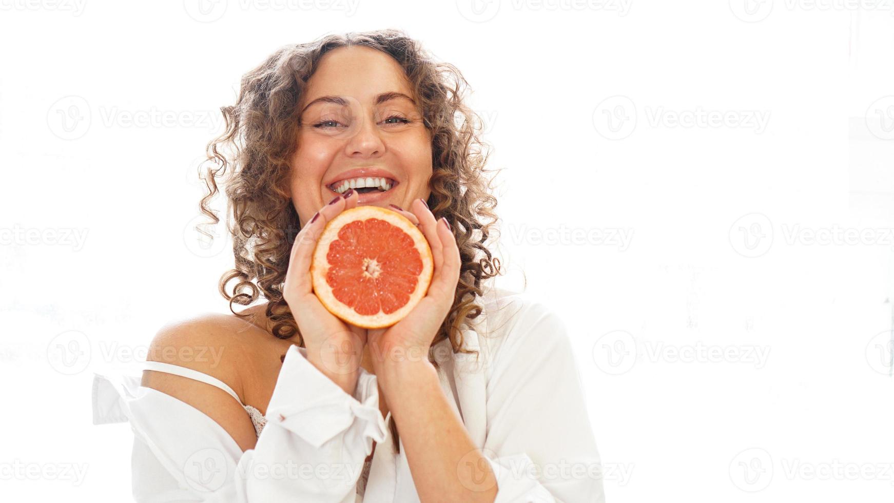 Portrait of pretty middle-aged woman with curly hair with grapefruit photo