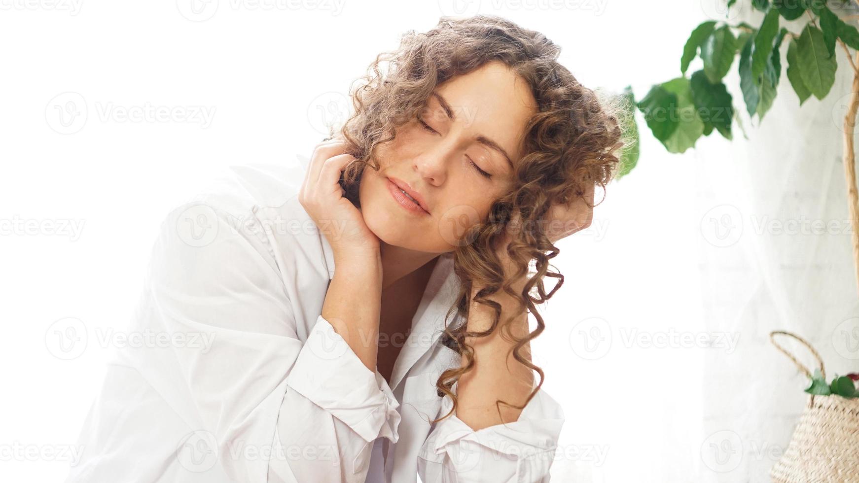 Woman sitting at home with plants and smiling at camera photo