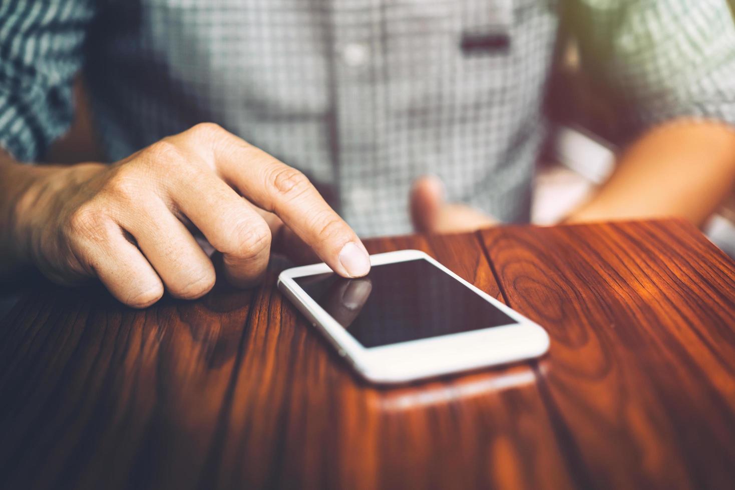 Businessman hand using mobile phone at coffee shop in morning light photo