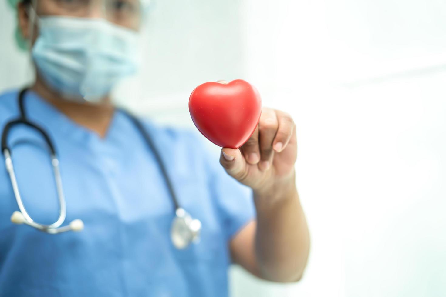 médico asiático con traje de ppe para proteger el coronavirus con corazón rojo foto