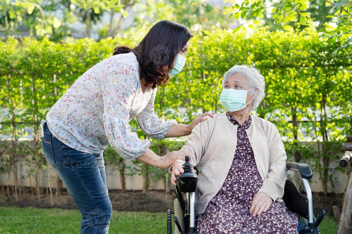 Ayudar a la mujer mayor asiática en silla de ruedas eléctrica foto