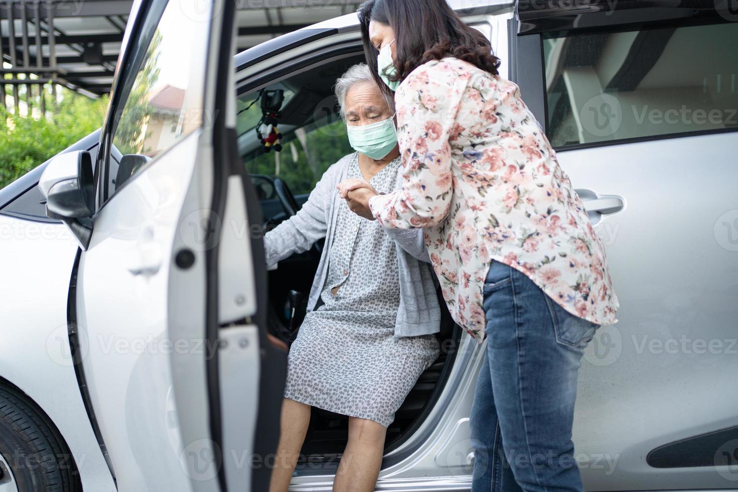 Ayudar y apoyar a la paciente asiática senior mujer prepararse para llegar a su coche foto