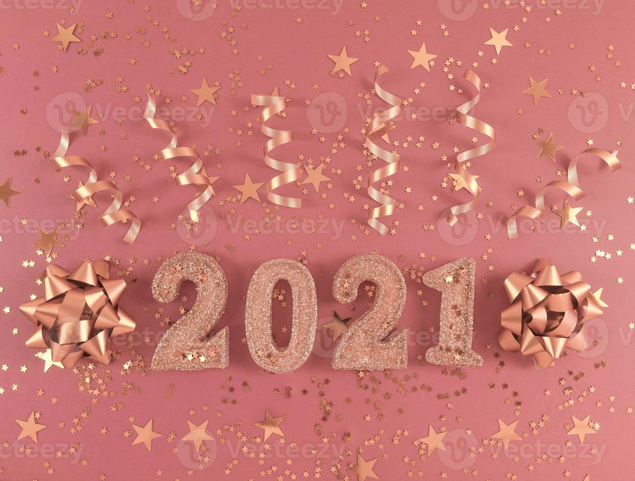 Glittered figures 2021, stars, bows and ribbons on pink background. photo