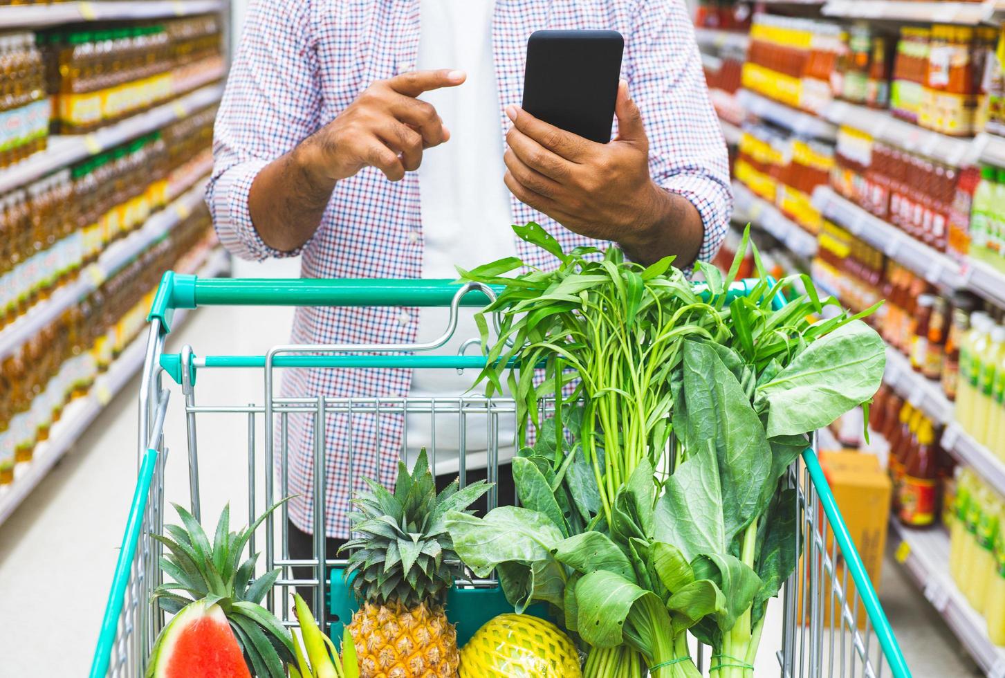 young-man-using-smartphone-while-shopping-at-supermarket-free-photo.jpg