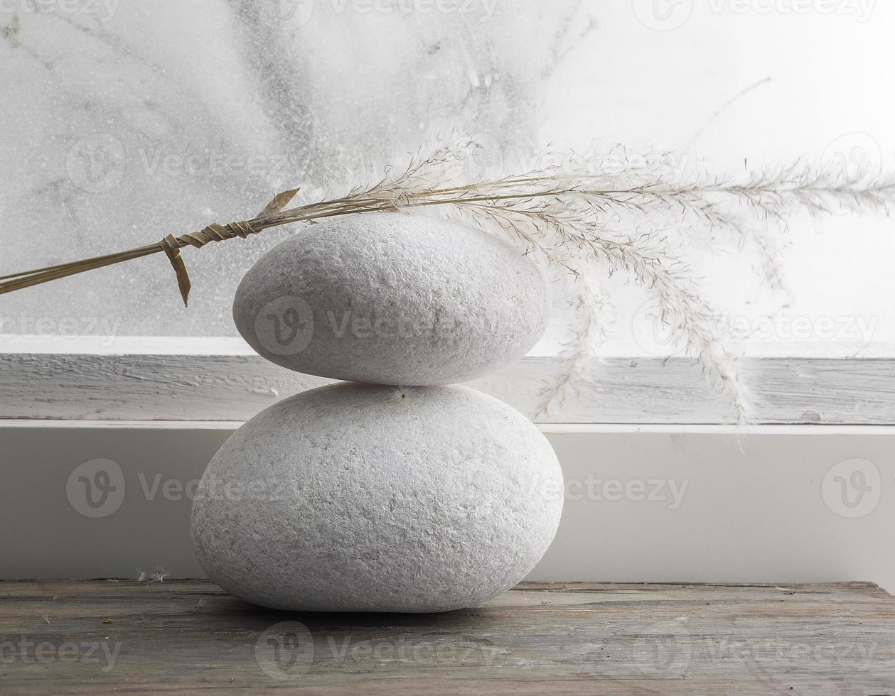 Dried rushes on top of two white pebble stone. photo