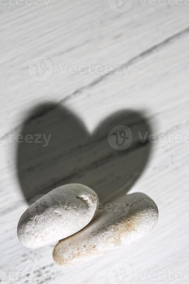 Rocks with a heart shaped shadow on a wooden surface. photo