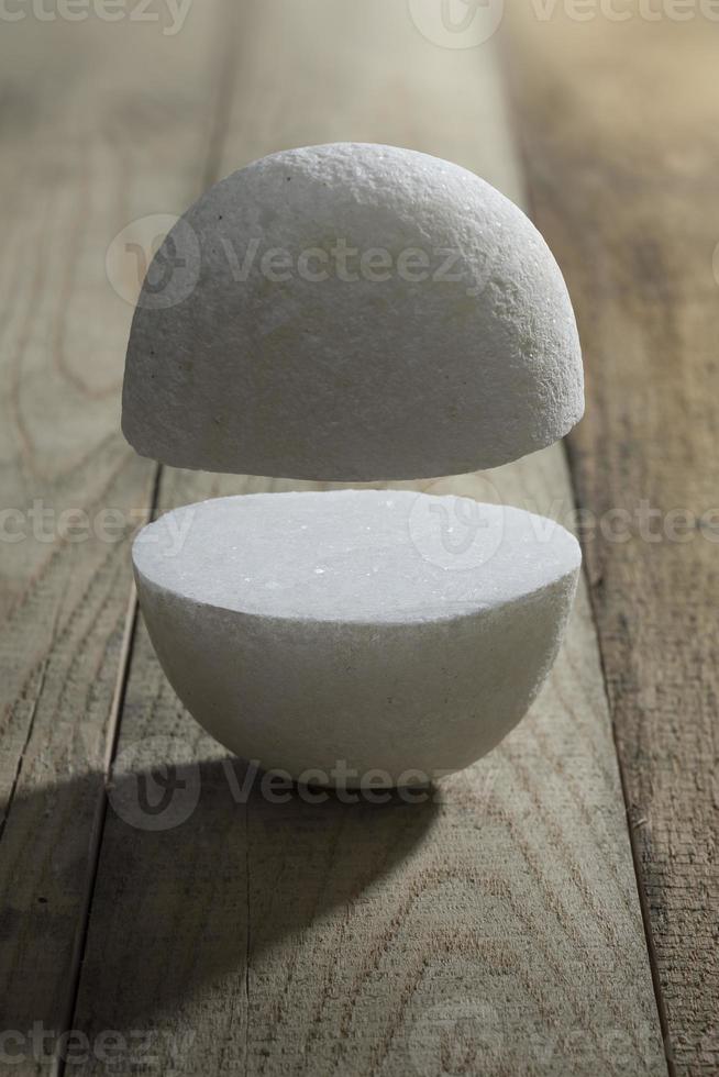 White stones in cut to two part on a wooden surface photo