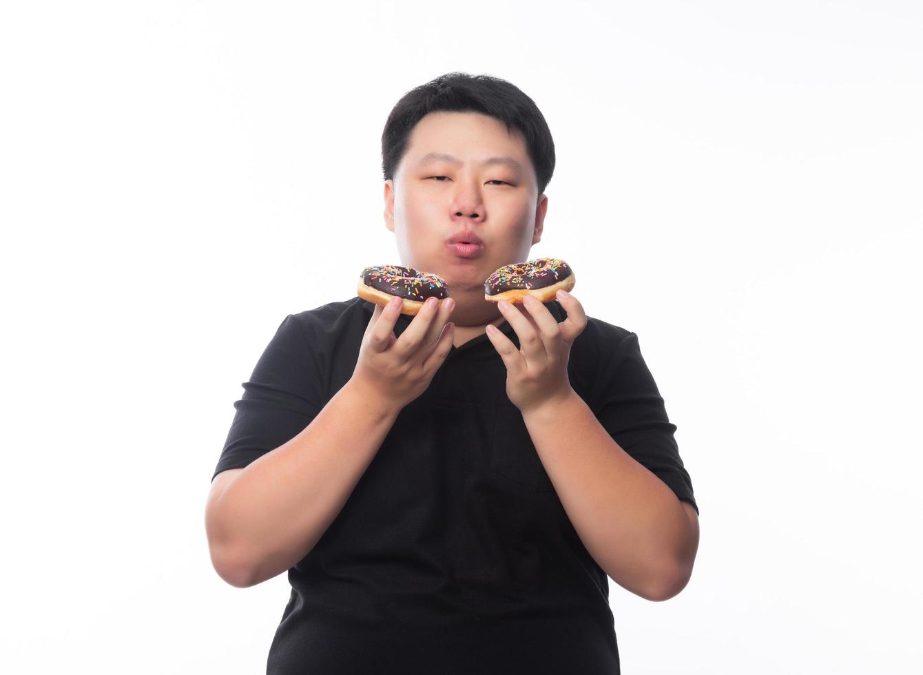 Young funny fat Asian man eating chocolate donuts photo