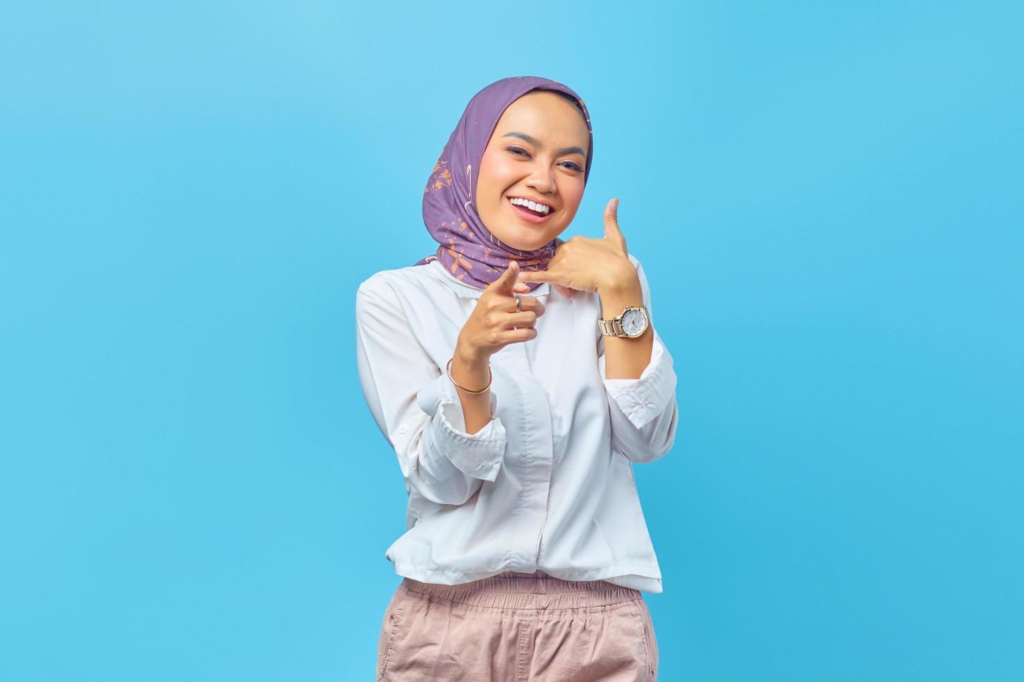 Hermosa mujer asiática sonriendo haciendo gesto de llamada con la mano foto