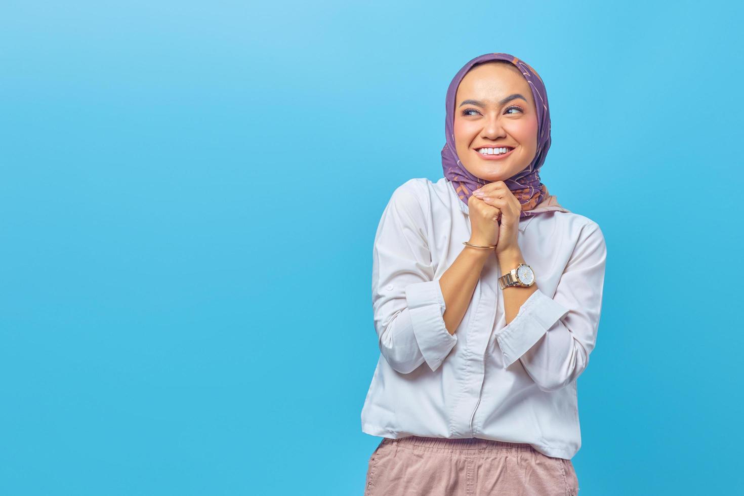 Asian woman looking cheerfully aside with folding raised hand photo