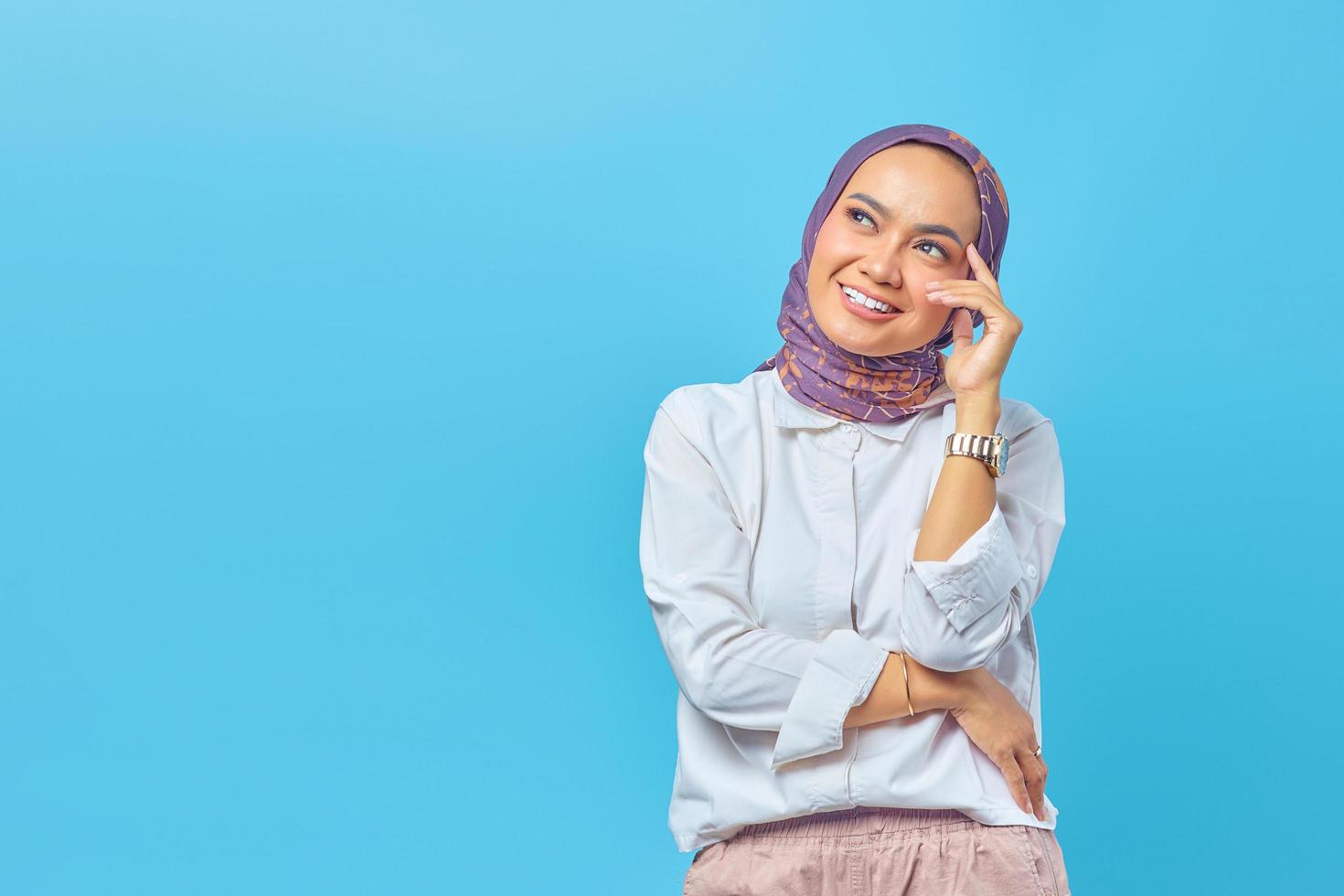 Beautiful Asian woman thinking of an idea isolated on blue background photo