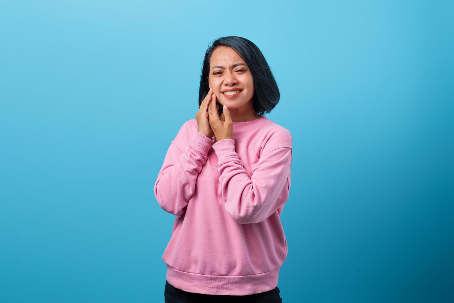 Asian woman touching cheek while suffering from terrible toothache photo