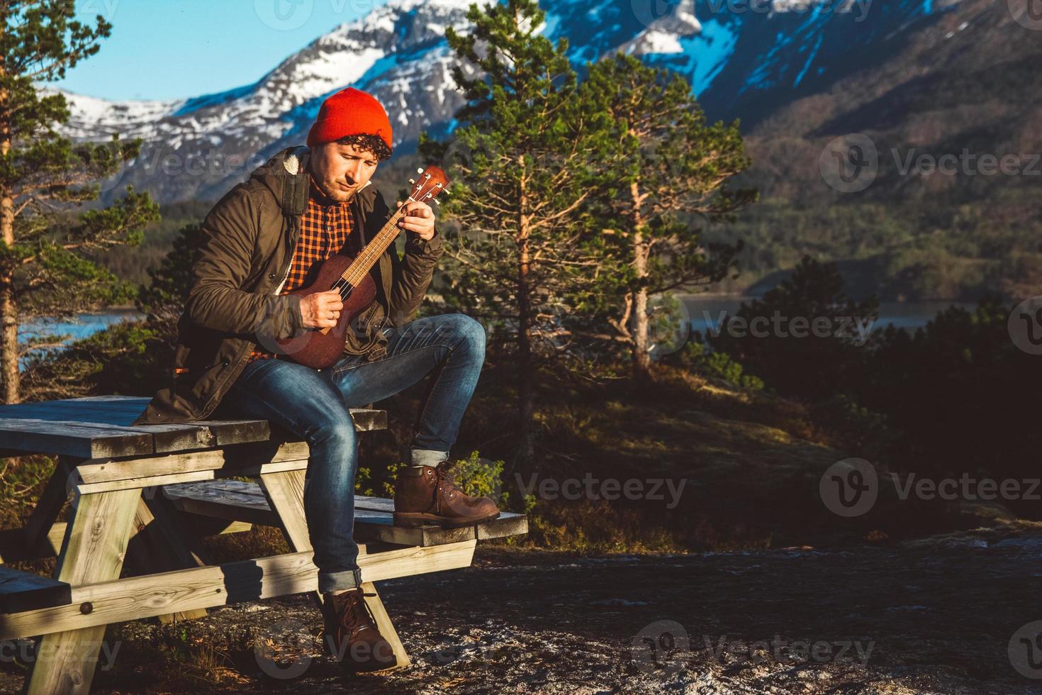 Guy playing guitar against the background of mountains, forests photo