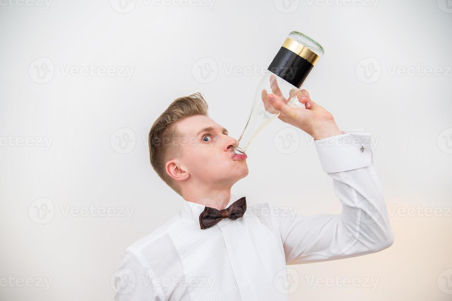 Young man drinking from glass bottle against a white background photo