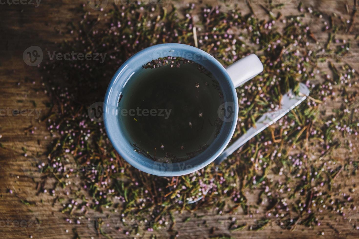 Cup and spoon with flowered tea on a wooden background photo