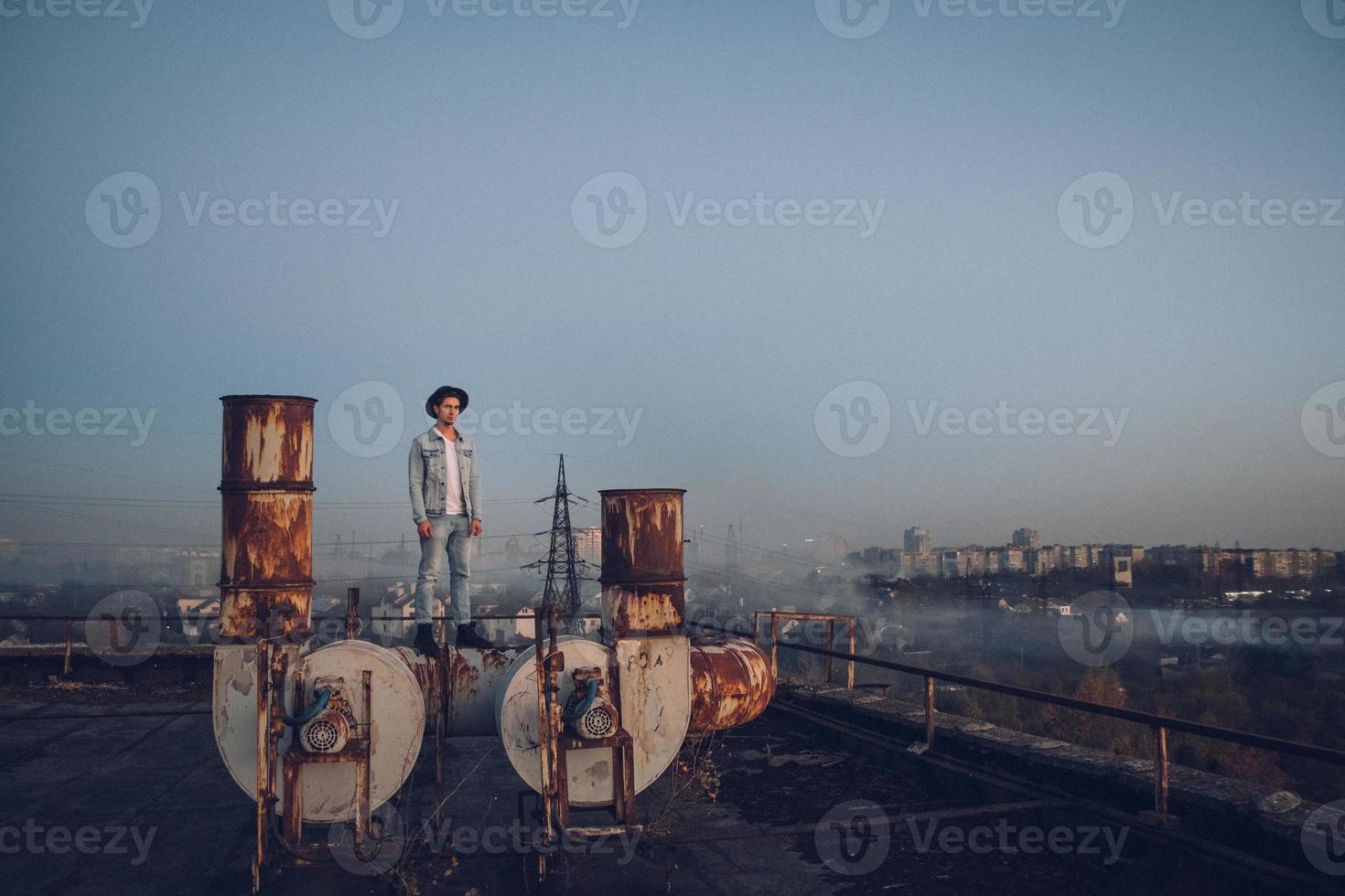 Hombre con sombrero vestido con camisa blanca y jeans en el fondo de la ciudad foto