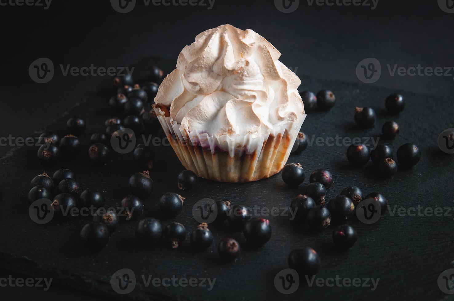Muffin on a black background with currant berries. photo