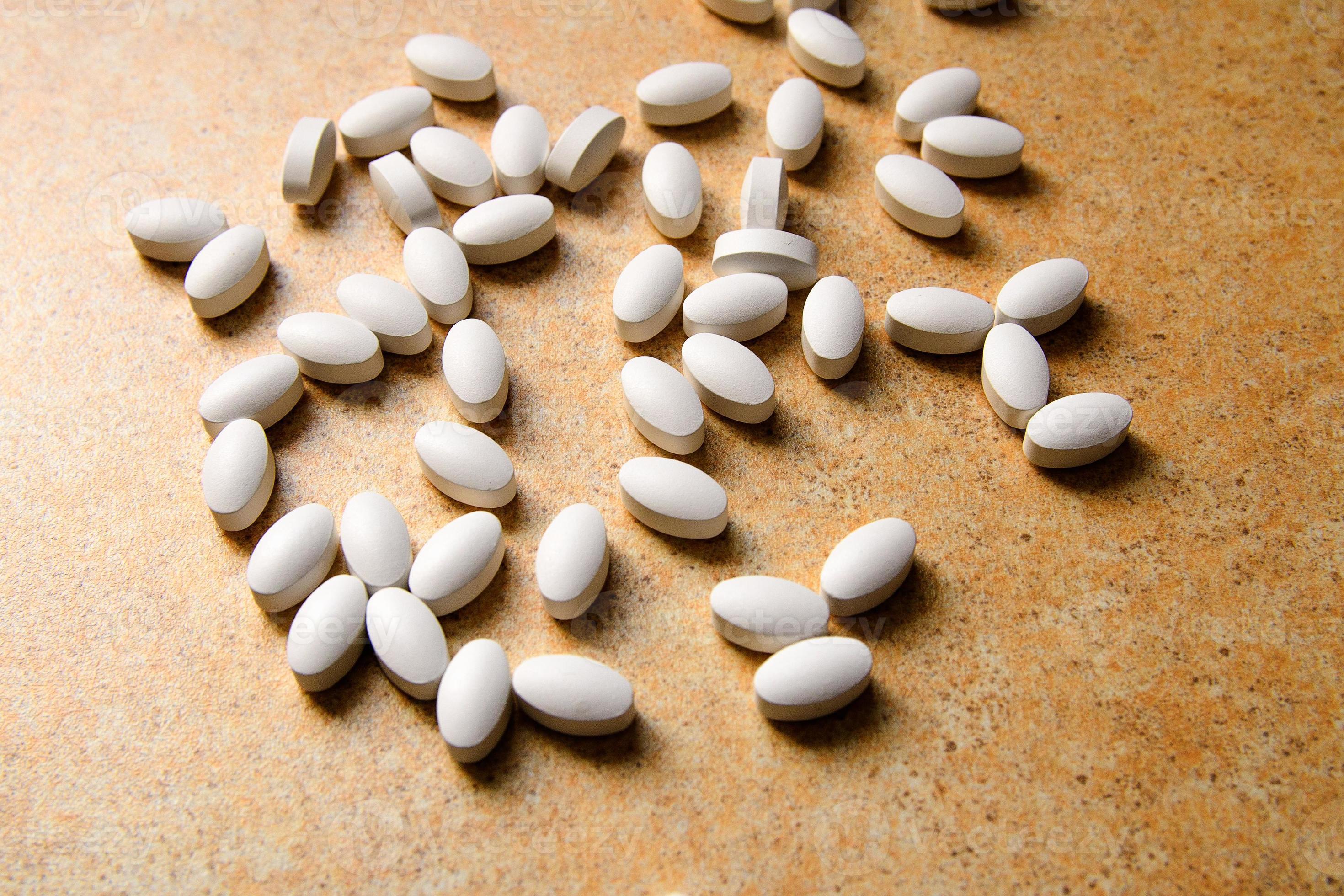 Las píldoras de vitamina D yacen caóticamente contra una encimera de arena. foto