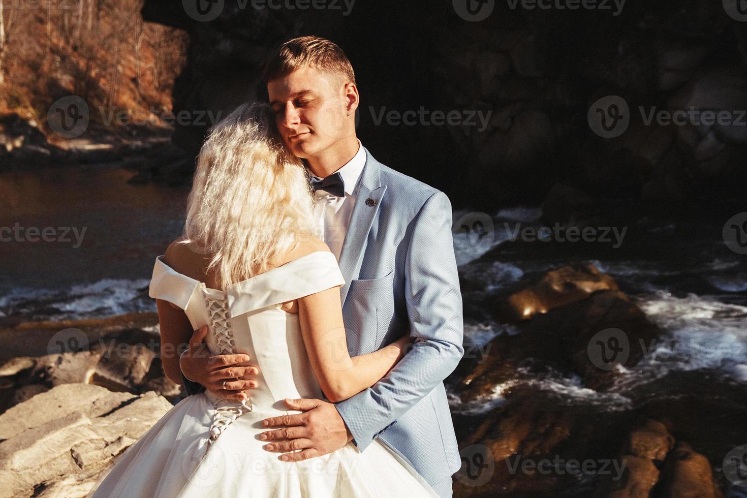 Married couple embracing with a mountain and river background photo